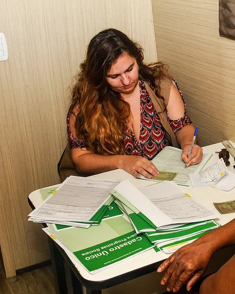 Técnica e usuária preenchendo documentos do CRAS