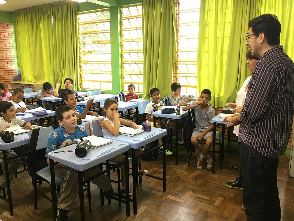Sala de aula de escola municipal com alunos nas carteiras e um professor em pé