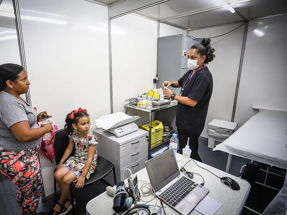 Profissional de saúde atendendo uma mãe e uma criança numa unidade de saúde